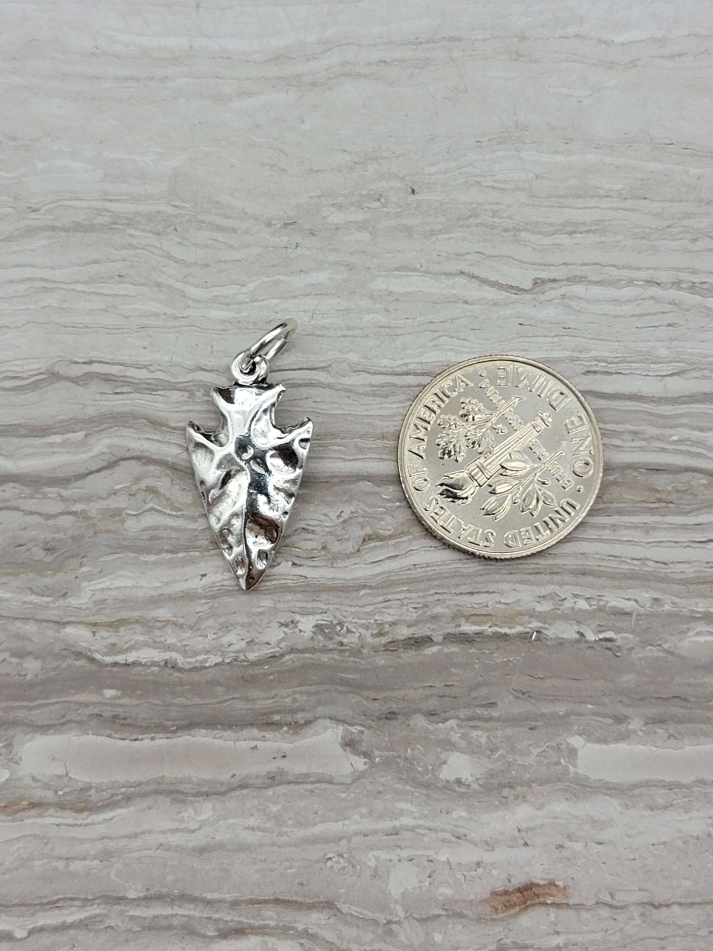 silver arrowhead charm with a shiny finish