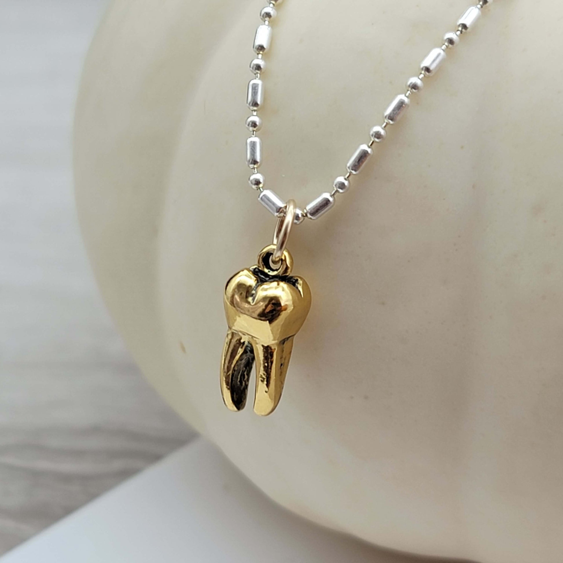 Gold tooth pendant charm on a silver necklace