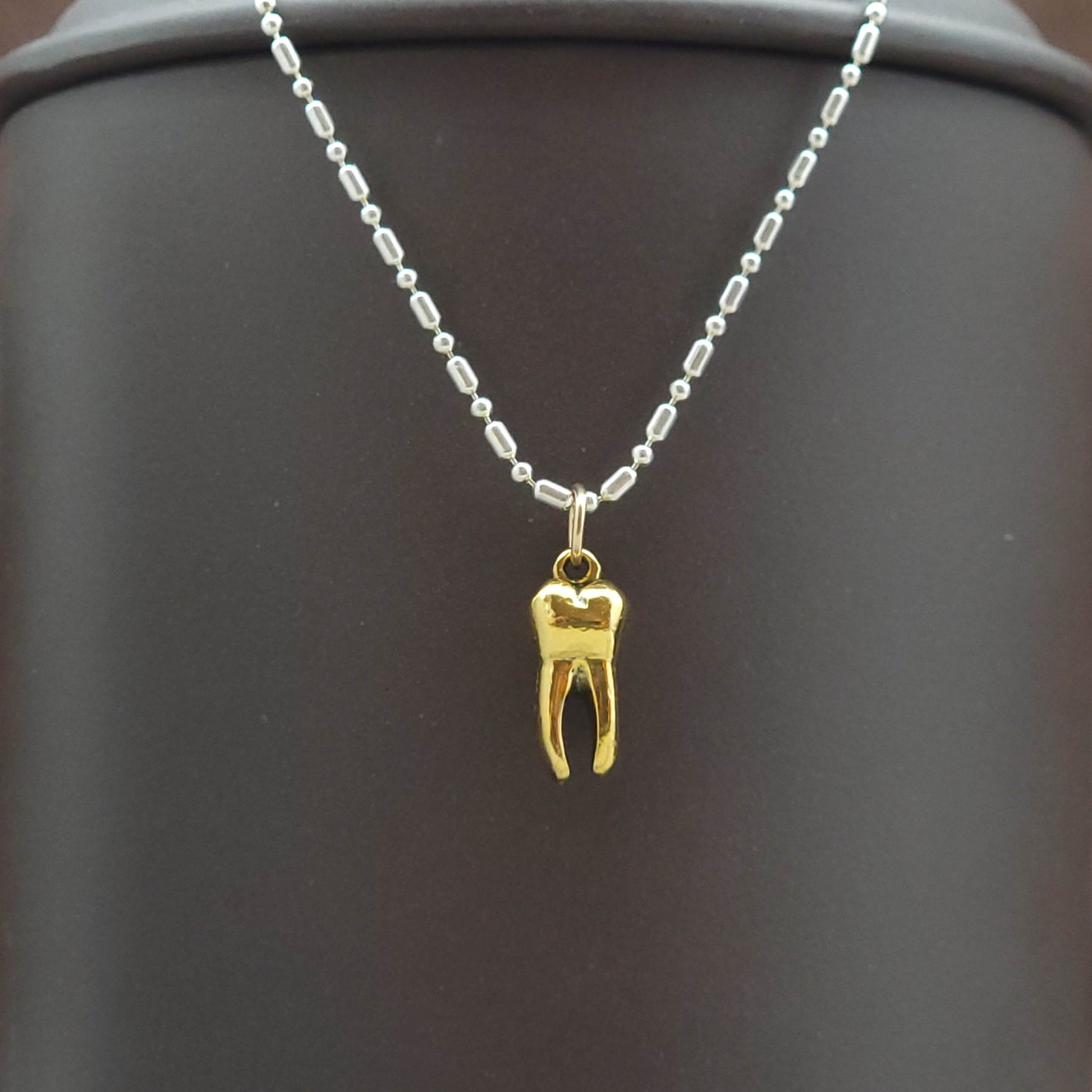 Gold tooth pendant charm on a silver necklace