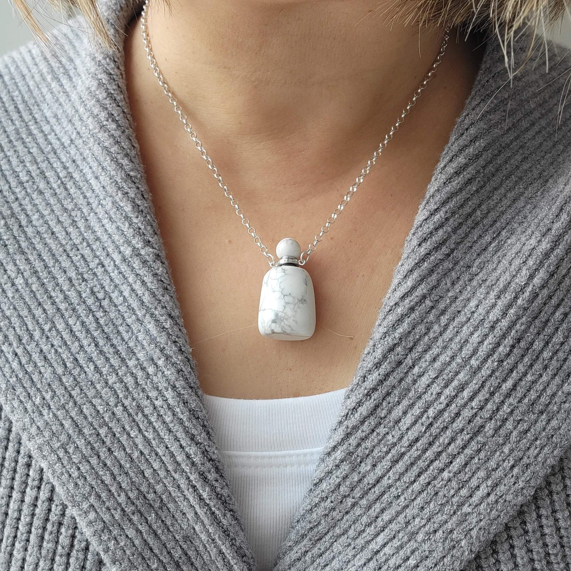 Necklace with a white turquoise pendant worn by a person in a gray sweater.