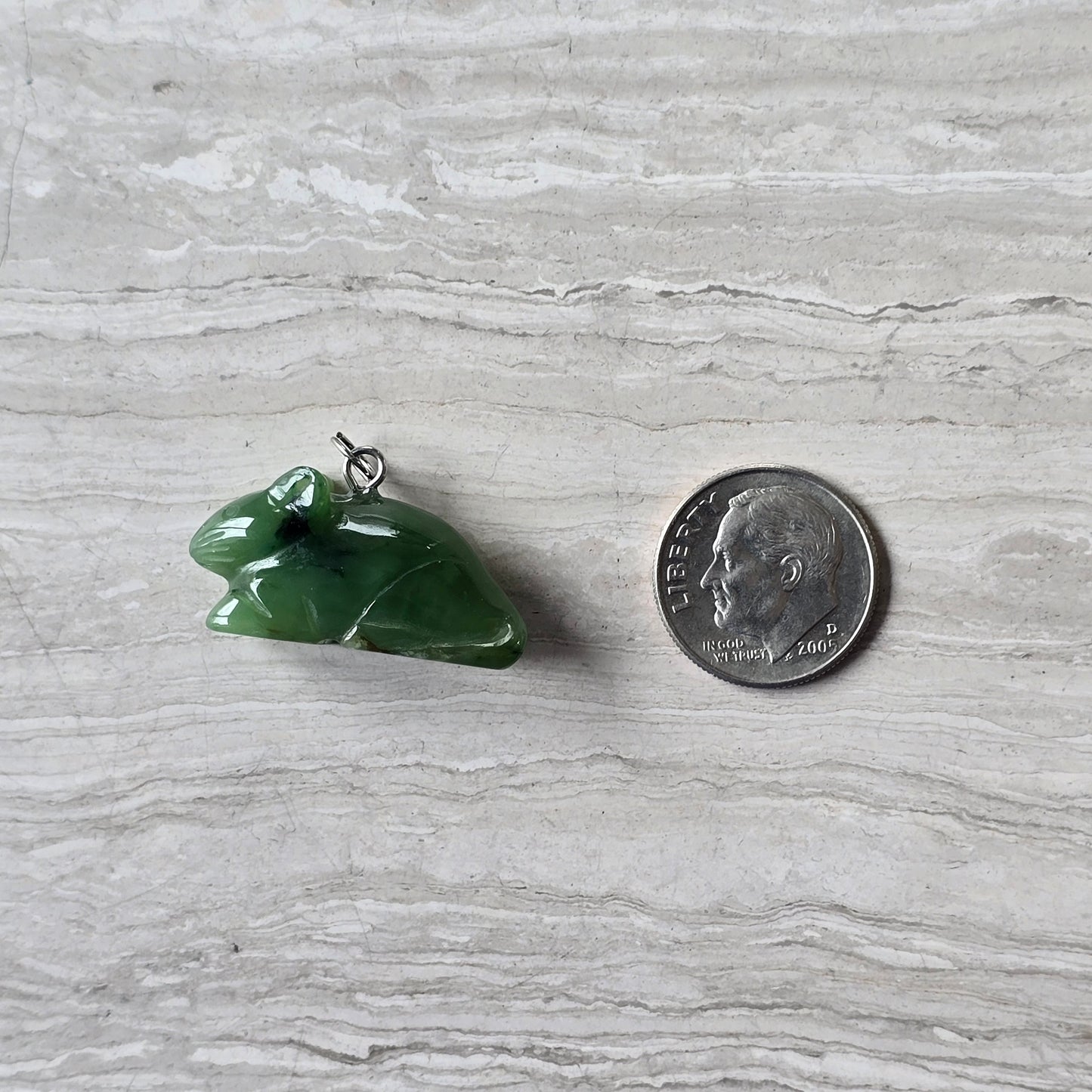 jade rat charm next to a dime