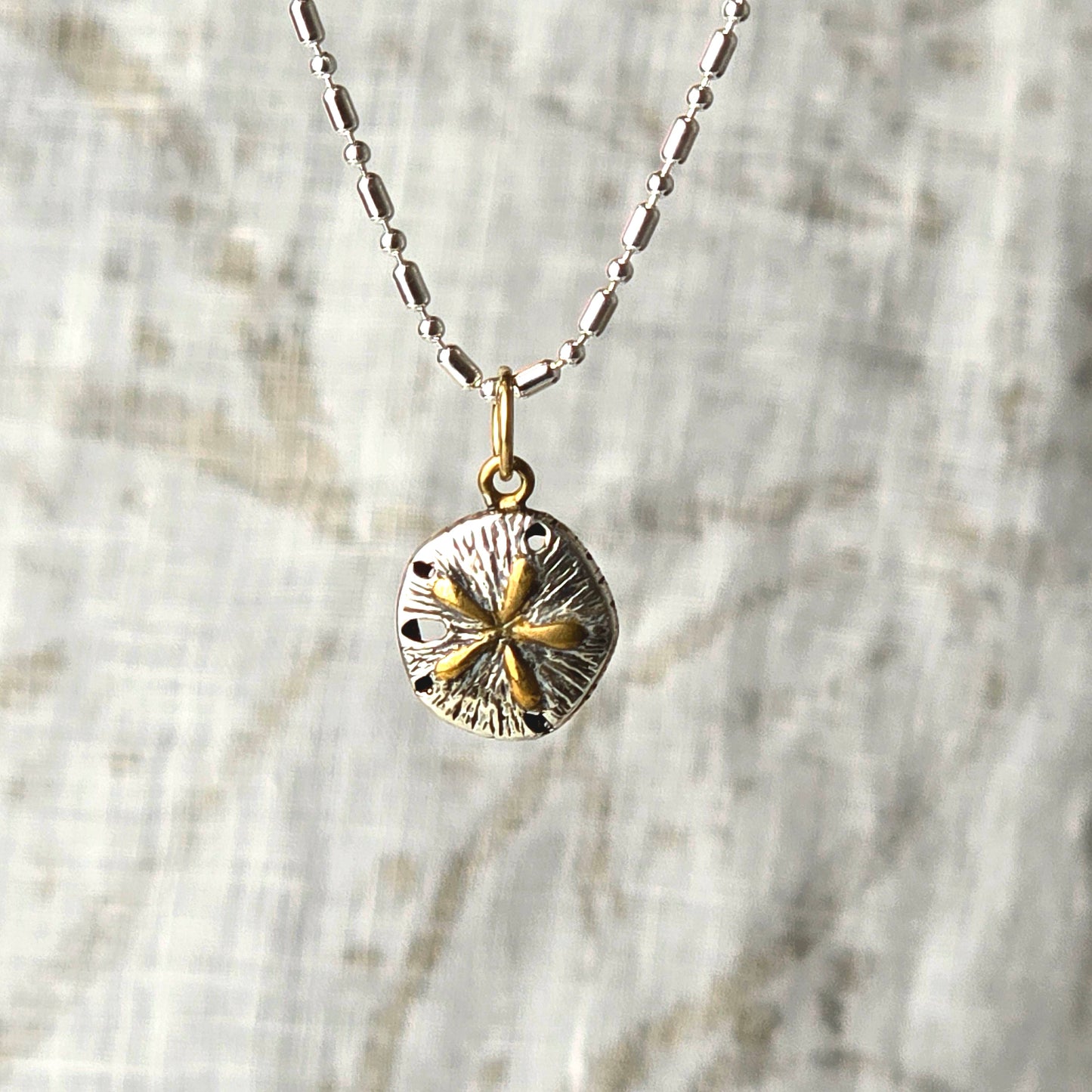 silver and gold sand dollar charm