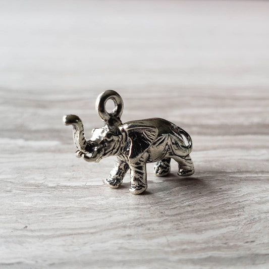 A silver charm pendant shaped like an elephant, crafted from solid sterling 925 silver, displayed on a wooden surface.