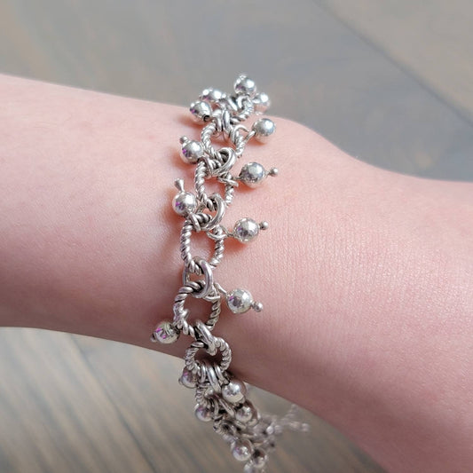 A sterling silver beaded bracelet with twist wire design and a clasp, displayed on a wrist.