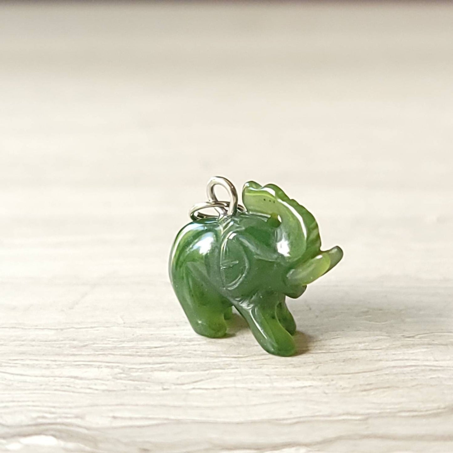 A genuine jade elephant charm hand-carved from nephrite jade, displayed on a sterling silver rolo chain.