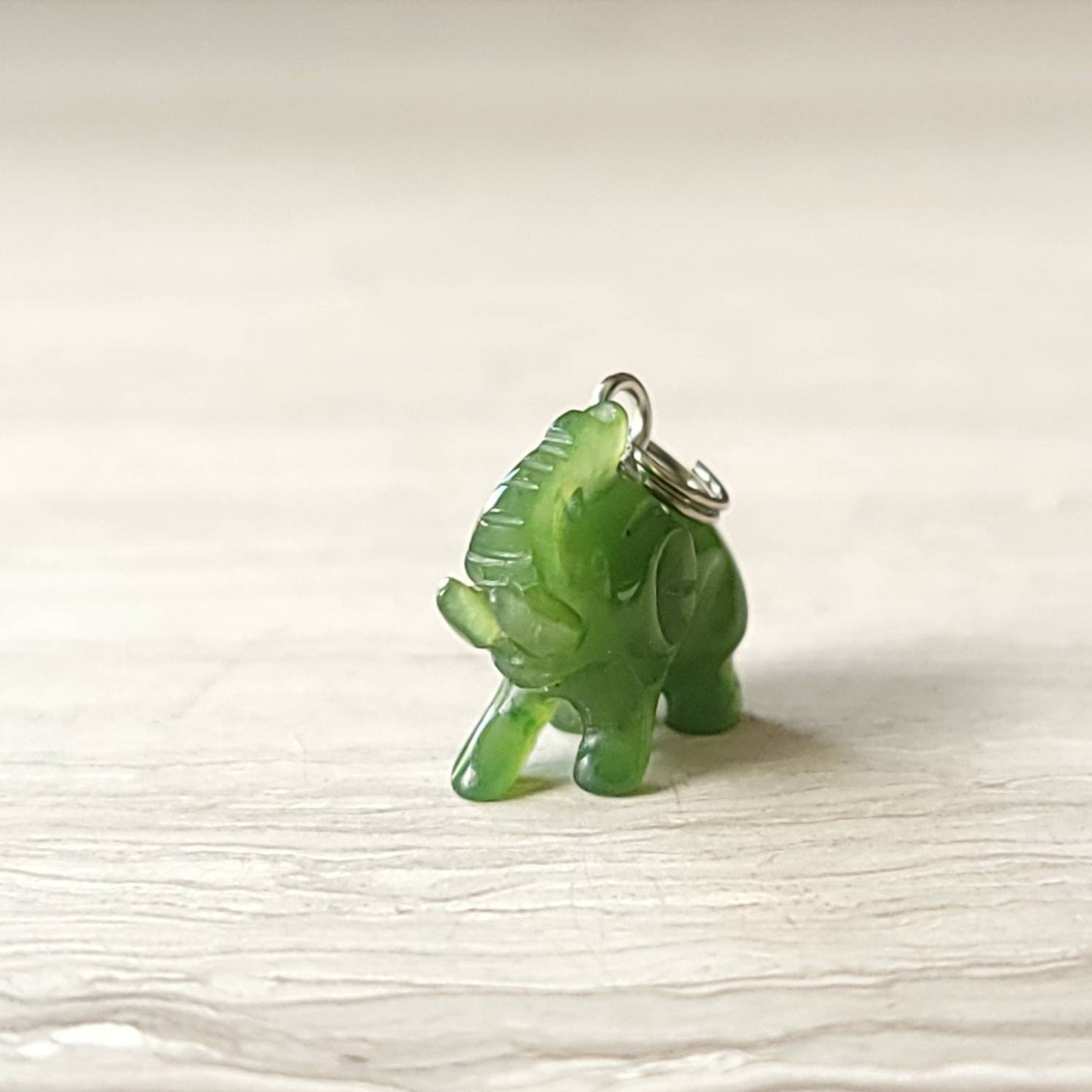 A genuine jade elephant charm hand-carved from nephrite jade, displayed on a sterling silver rolo chain.