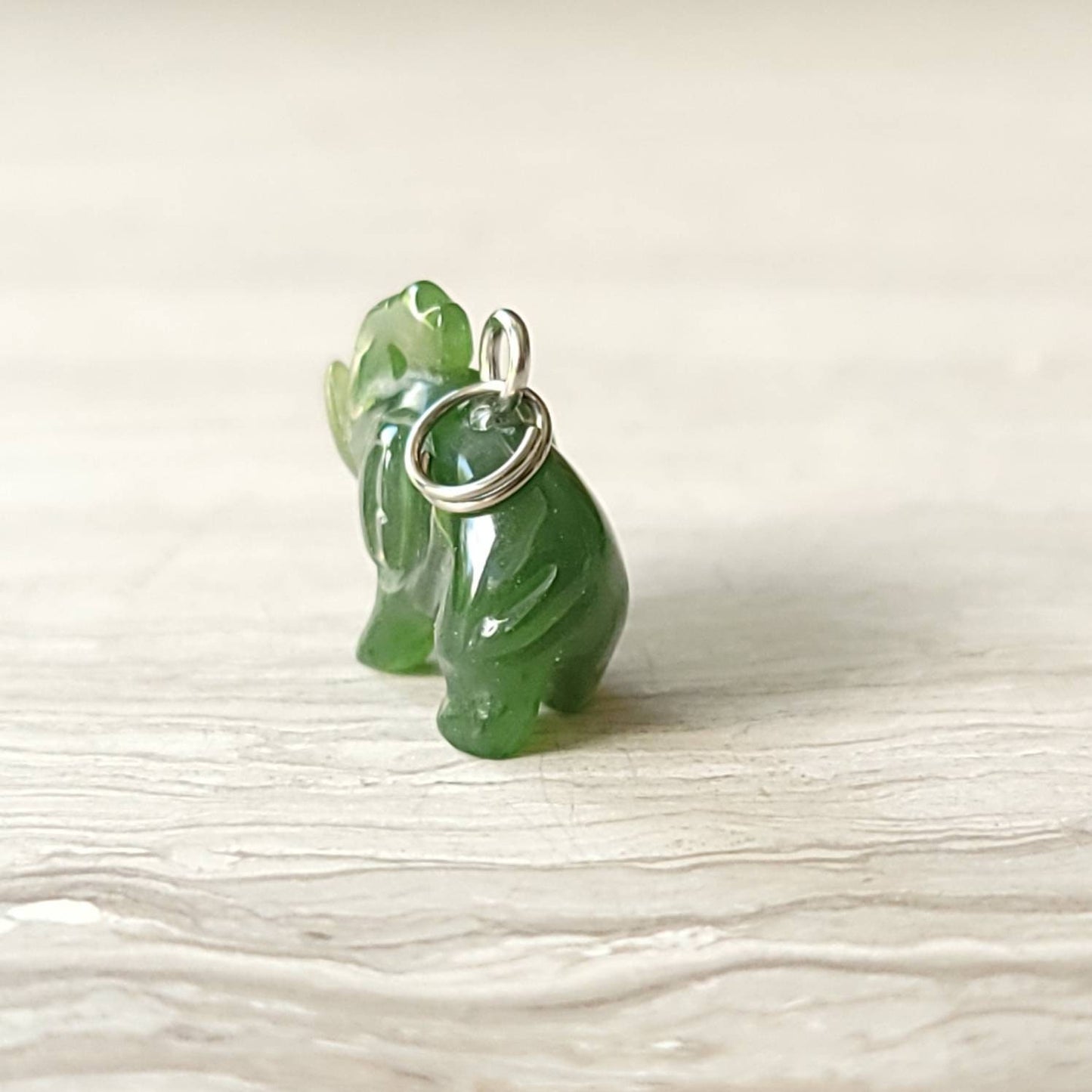 A genuine jade elephant charm hand-carved from nephrite jade, displayed on a sterling silver rolo chain.