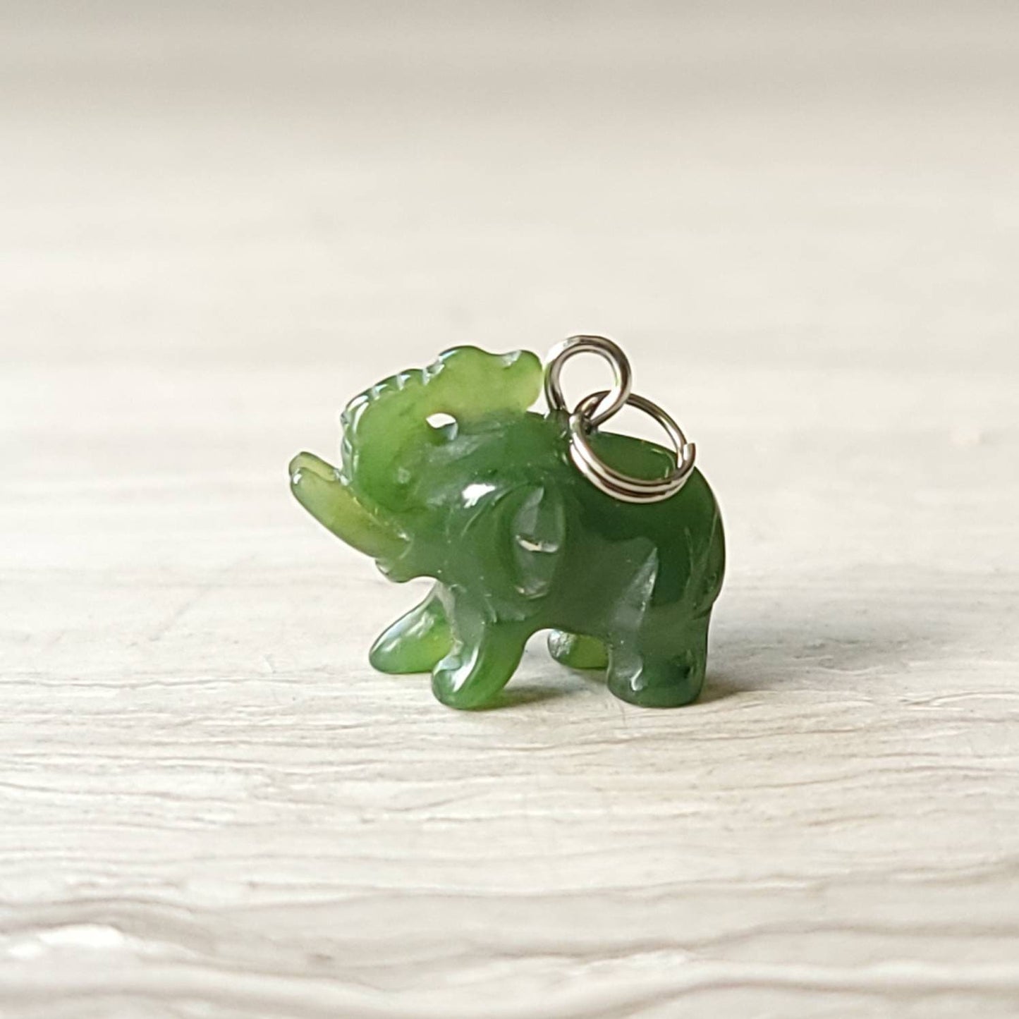 A genuine jade elephant charm hand-carved from nephrite jade, displayed on a sterling silver rolo chain.