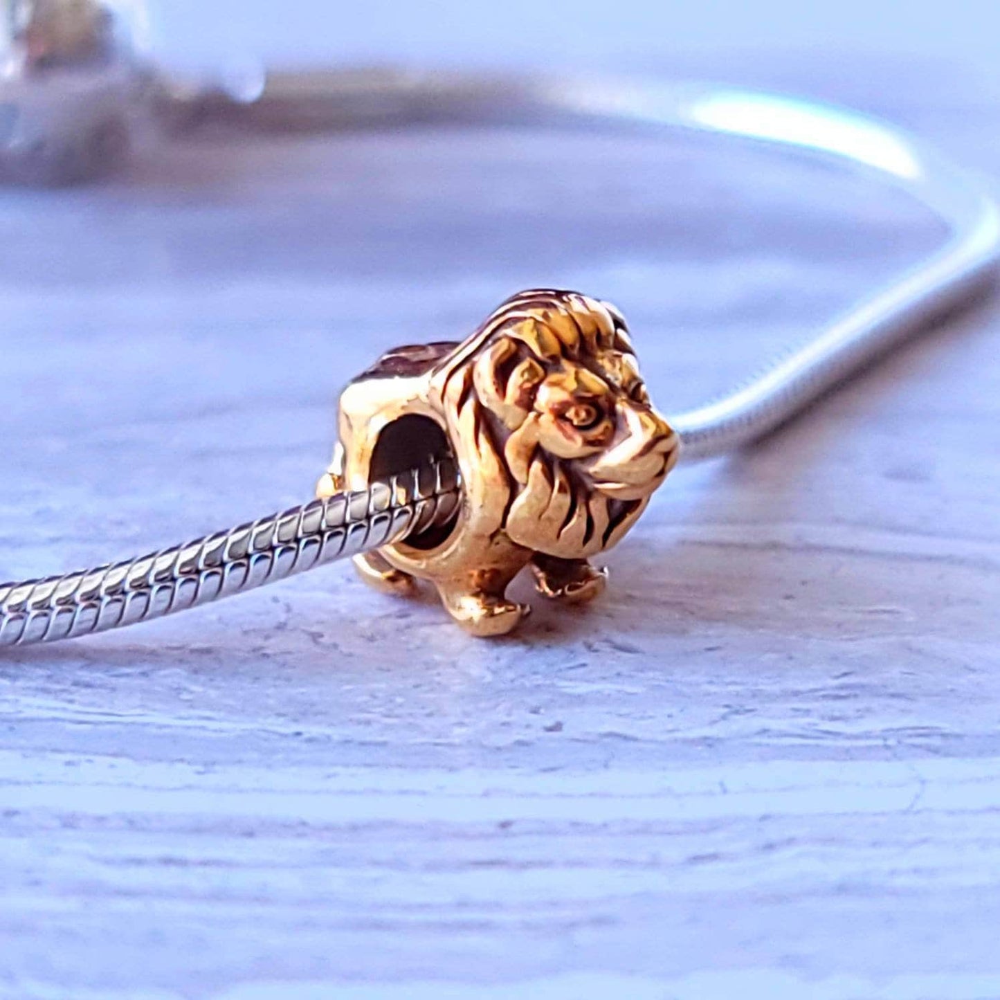 Gold lion charm spacer bead with a silver bracelet charm, featuring a detailed lion's head design on a gold plated 925 silver base.