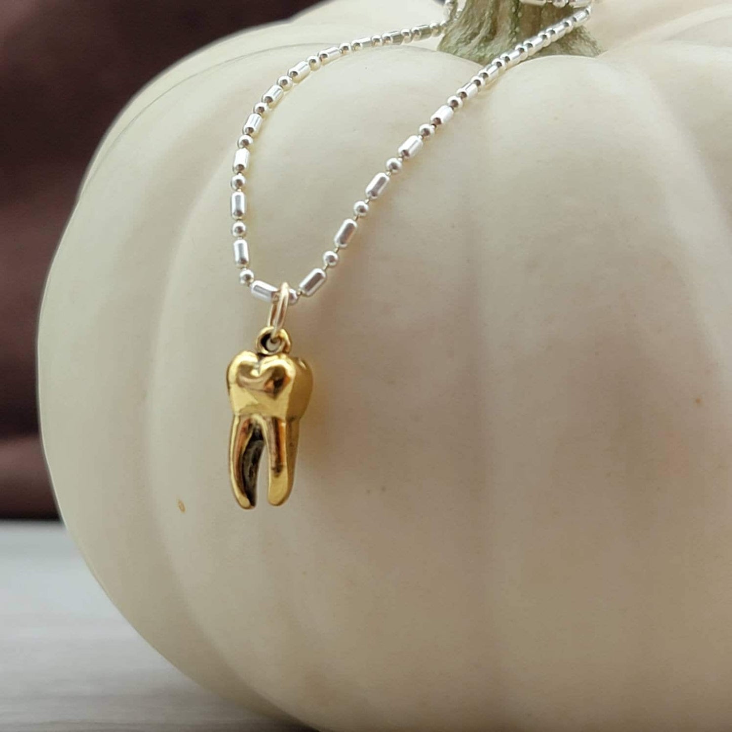 Gold tooth pendant charm on a silver necklace