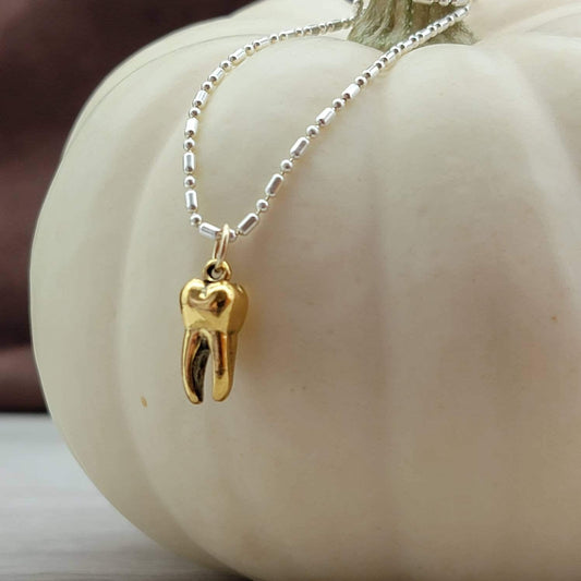 Gold tooth pendant charm on a silver necklace