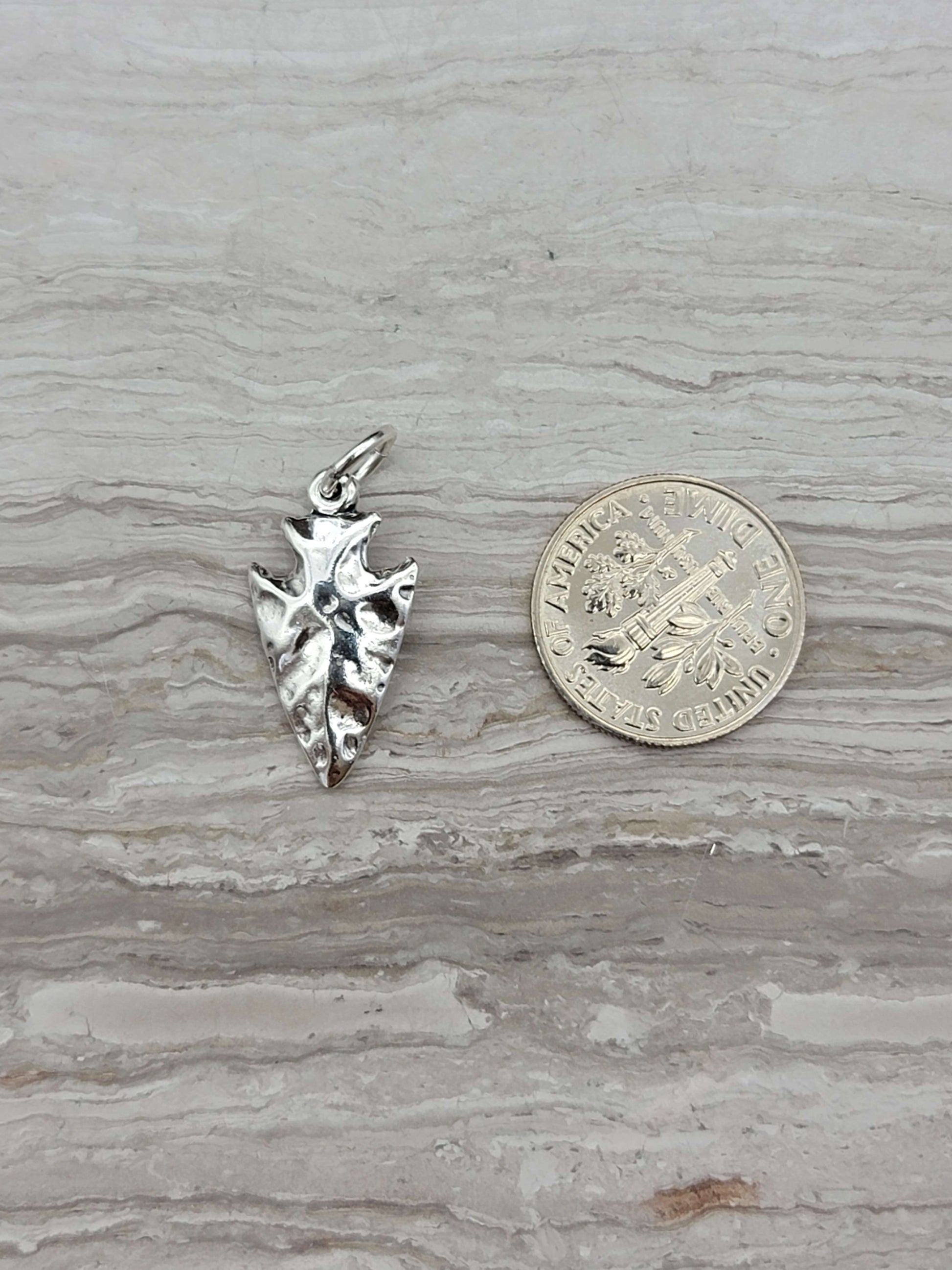 silver arrowhead charm with a shiny finish