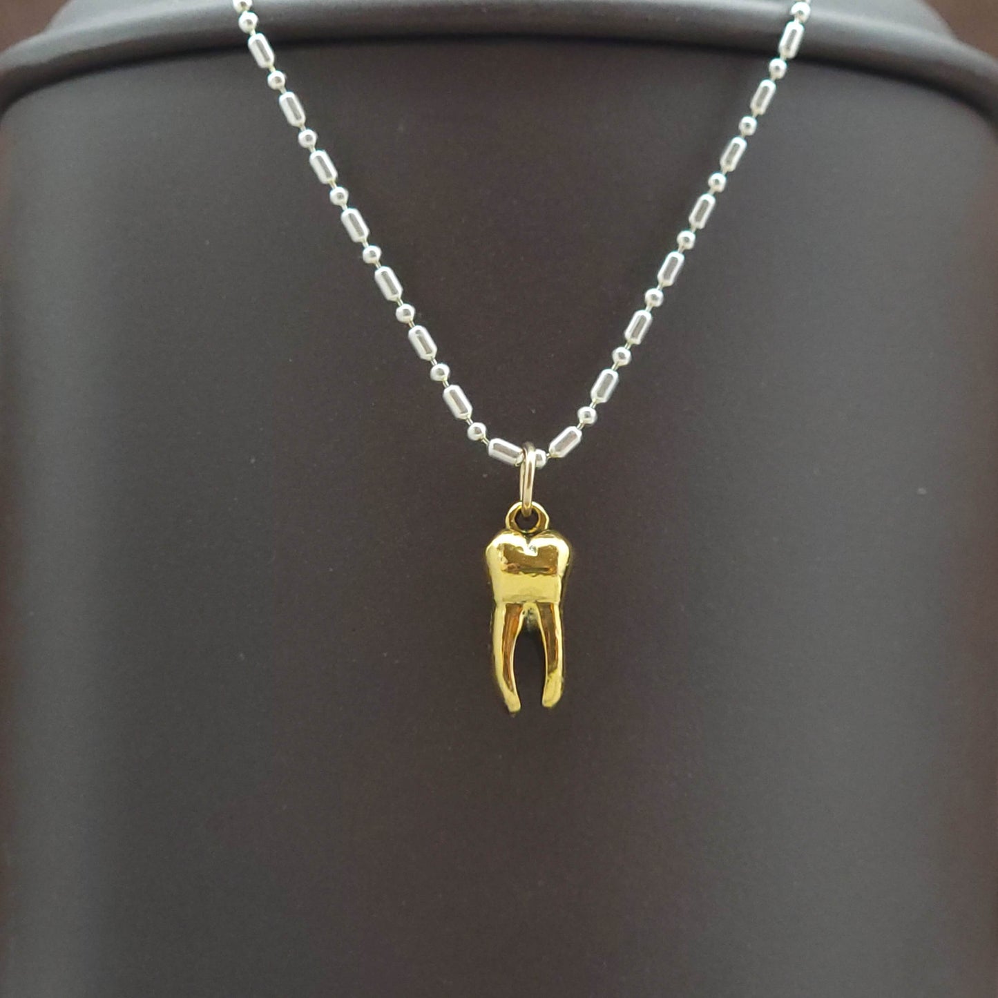 Gold tooth pendant charm on a silver necklace