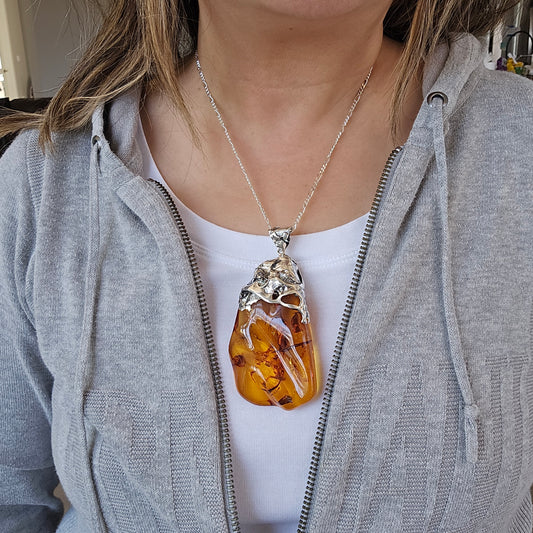 Baltic Amber Pendant set in hand formed silver bail, large statement sized polished raw Baltic Amber necklace. Baltic Amber necklace worn by model