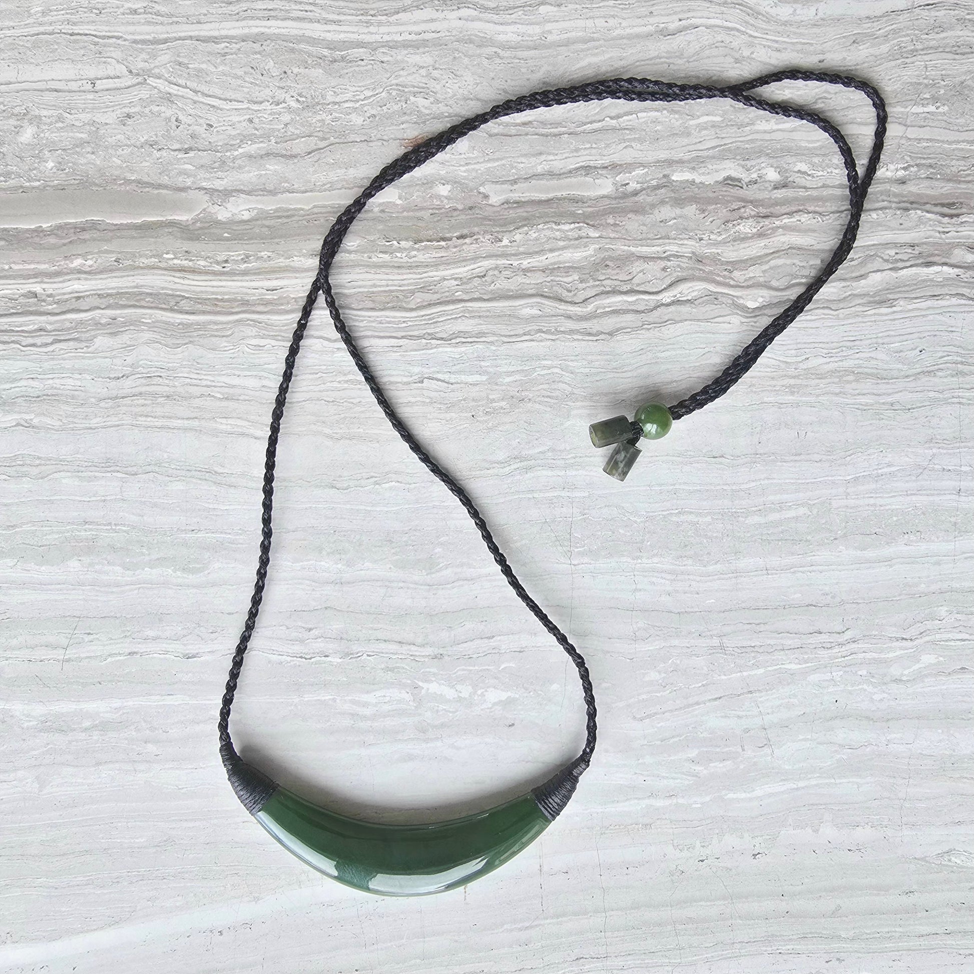 Green jade crescent necklace with a black waxed adjustable cord necklace.