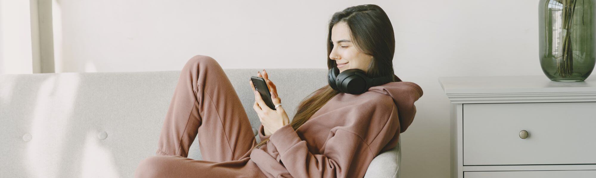 Woman sitting on a couch using a smartphone in a cozy living room.